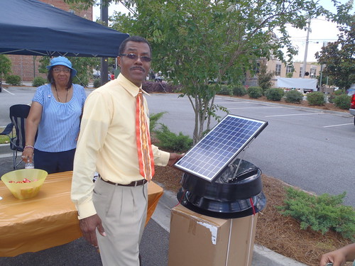 A man standing next to a solar panel measuring temperature.