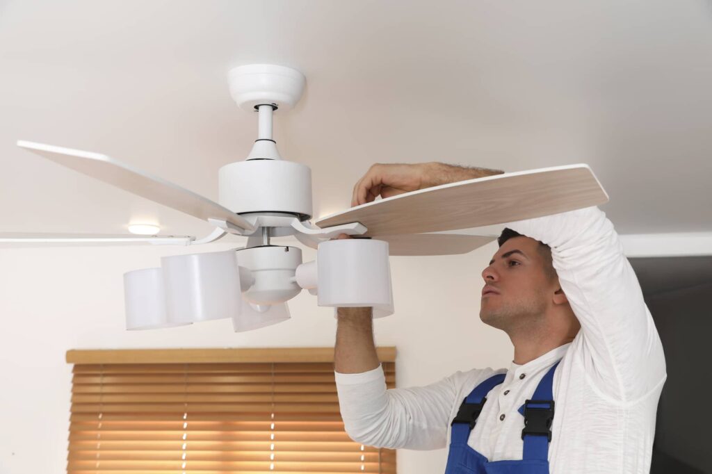 Man ficing a white ceiling fan with light fixture